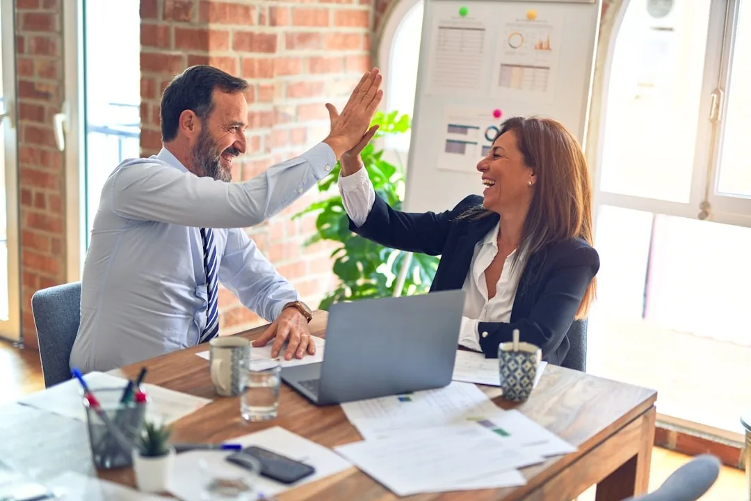 Two business professionals high-five after integrating proposal management software.