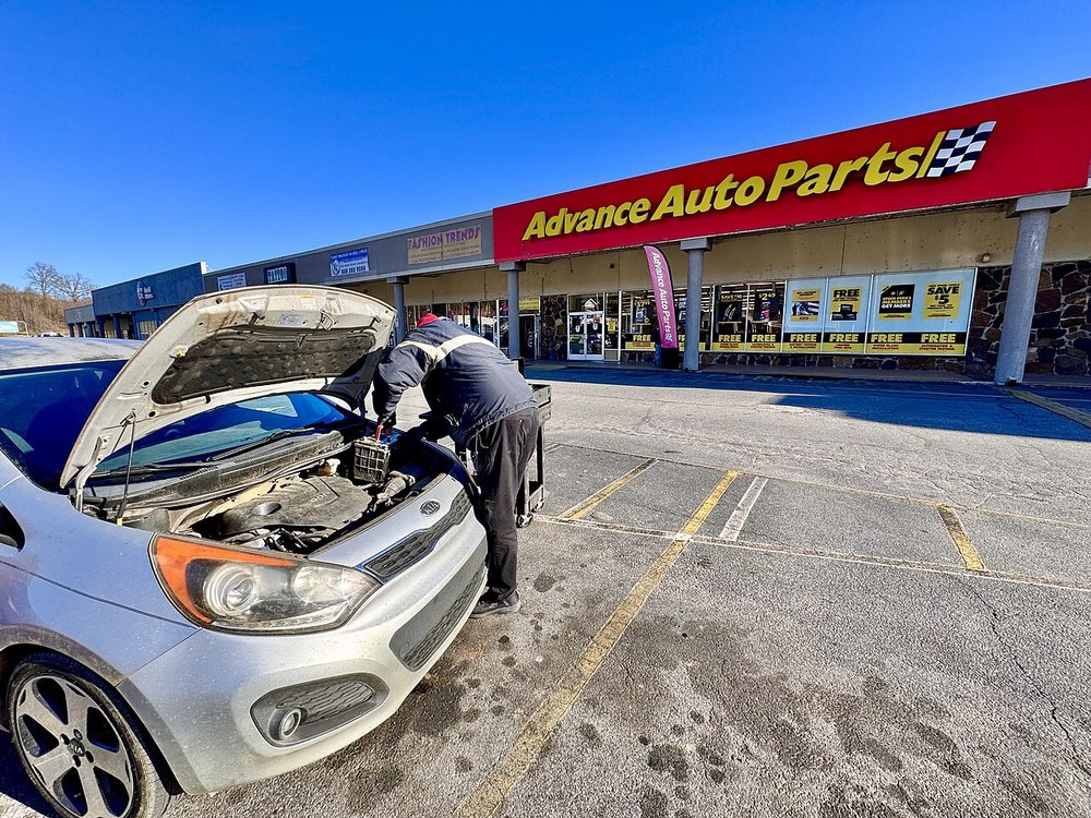 An Advance Auto Parts employee changing a car battery in the store parking lot